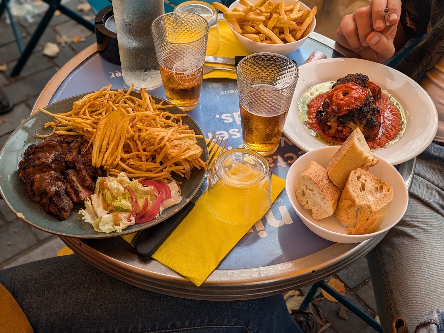 Une table de bistrot avec viande, légumes, frites et pain